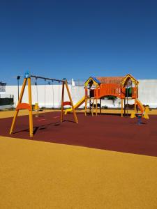 un parque infantil con 2 columpios y un columpio en Villa Figueira, en Portimão