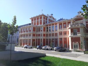 un grand bâtiment rouge avec des voitures garées devant lui dans l'établissement HEMNES Apartman, à Kaposvár