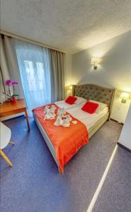 a bedroom with a bed with two stuffed animals on it at Great Polonia Jelenia Góra City Center in Jelenia Góra