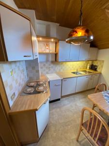 a kitchen with white cabinets and a table and aendant light at Goldengel Ferienwohnung im Herzen Kalterns mit einer Terasse zum verlieben in Caldaro