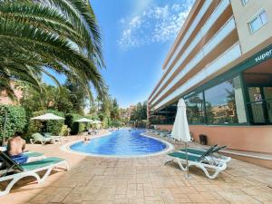 a swimming pool with lounge chairs and a building at Aparthotel SunClub Salou in Salou