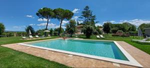 una piscina en un patio con sillas y árboles en Agriturismo Poderedodici, en Orbetello