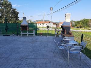 eine Terrasse mit Stühlen, Tischen und einem Grill in der Unterkunft EL CINCHO - LA COLINA in Arnuero