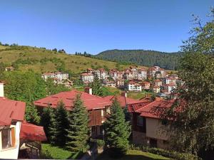 un groupe de maisons sur une colline plantée d'arbres dans l'établissement Rodopi Houses, à Chepelare