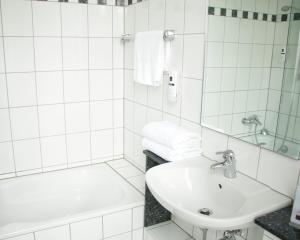 een witte badkamer met een wastafel en een bad bij Z&B Hotel in Trier