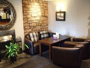 une salle d'attente avec une table et des fauteuils en cuir dans l'établissement Inchture Hotel, à Dundee