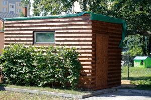 un pequeño cobertizo de madera con un techo verde junto a un arbusto en Vila ELIS, en Jeseník