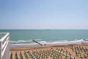 a beach with chairs and umbrellas and the ocean at Hotel Ancora in Lido di Jesolo