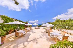 une terrasse avec des tables blanches, des chaises et des parasols dans l'établissement Gardenia Hotel, à Kaş