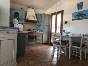 una cucina con armadi blu, tavolo e sedie di Villa Peonia a Budoni