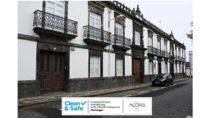 ein Gebäude mit Balkon und ein Auto, das auf einer Straße geparkt ist in der Unterkunft Casa do Campo de São Francisco in Ponta Delgada