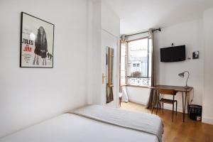 Habitación blanca con cama y escritorio en Zazie Hôtel, en París