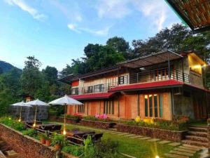 une maison avec des tables et des parasols devant elle dans l'établissement Bann Suan Maya, à Mae Rim