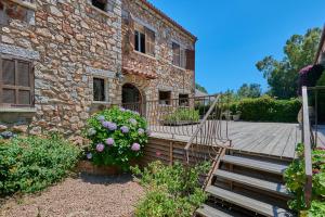 una casa in pietra con una scala in legno e fiori di Hotel Shegara a Porto Vecchio