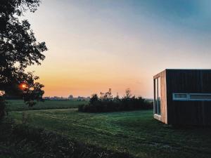 um pequeno edifício num campo com o pôr-do-sol ao fundo em Hotel & Restaurant Weidumerhout em Weidum