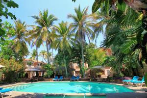 a swimming pool in front of a resort with palm trees at Hotel Santa Fe in Puerto Escondido