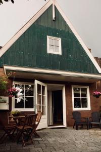 uma casa com telhado verde, cadeiras e uma mesa em Slapen bij Jesse em Broek in Waterland