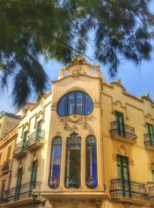 un bâtiment jaune avec des fenêtres et un arbre dans l'établissement Hotel Noucentista, à Sitges