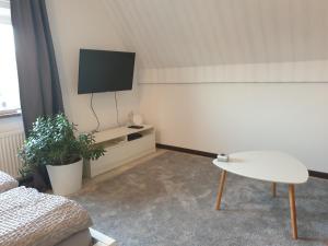 sala de estar con TV, sofá y mesa en Ferienwohnung Möwenblick, en Flensburg