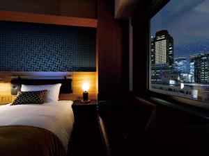 1 dormitorio con cama y ventana con vistas al perfil urbano en DEL style Osaka Shin Umeda by Daiwa Roynet Hotel, en Osaka