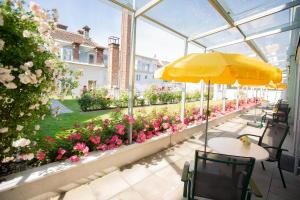 - une terrasse avec une table, un parasol et des fleurs dans l'établissement Hotel Gollner, à Graz