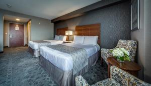 a hotel room with two beds and chairs at Monte Carlo Inn Markham in Markham