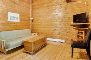 een slaapkamer met een bed, een tv en een bureau bij Ingonish Chalets in Ingonish Beach