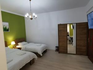 sypialnia z 2 łóżkami, lustrem i żyrandolem w obiekcie Ambient Deluxe Apartman w mieście Gyula