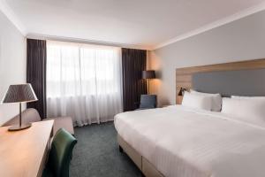 Radisson Hotel and Conference Centre London Heathrow في هيلينغدون: غرفة فندقية بسرير كبير ونافذة