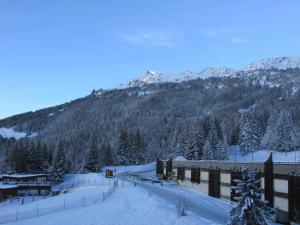 a snow covered mountain with trees and a building w obiekcie Residence Pierra Menta w mieście Arc 1800