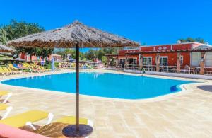 - une piscine avec un parasol et des chaises longues dans l'établissement Colina da Lapa & Villas, à Carvoeiro