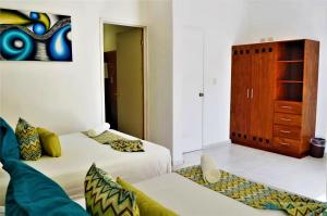 a room with two beds and a couch and a cabinet at Corales Suites in Puerto Morelos