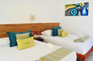 two twin beds in a room with two at Corales Suites in Puerto Morelos