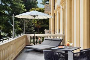 une terrasse avec un parasol, une table et des chaises dans l'établissement Grand Hotel Victoria concept & spa, by R Collection Hotels, à Menaggio