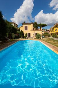 a blue swimming pool with a house in the background at Appartamento Villa Matone in Grottaferrata