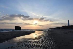 un tramonto su una spiaggia con riflesso nella sabbia di Entre pinos y playa a Matalascañas