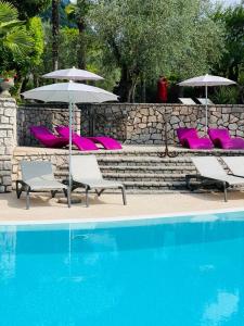 - un groupe de chaises longues et de parasols à côté de la piscine dans l'établissement Villa Miravalle, à Riva del Garda