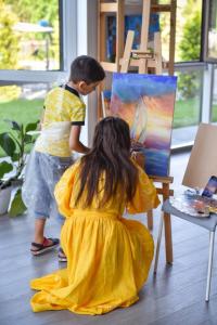 uma menina num vestido amarelo a pintar um quadro em Corner House em Odessa