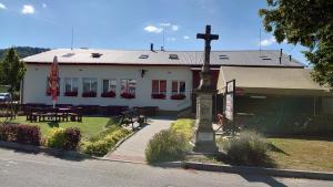 uma igreja com uma cruz em frente a um edifício em Na Rybníčku Bohutín em Bohutín