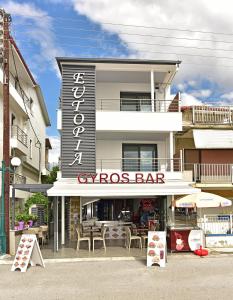 un bar gymos avec des tables et des chaises en face d'un bâtiment dans l'établissement EUTOPIA HOTEL, à Paralia Katerinis