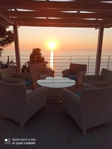 een patio met banken en een tafel met uitzicht op de zonsondergang bij Okeanos Luxury Villas - Resort in Athanion