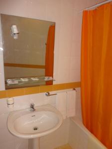 La salle de bains est pourvue d'un lavabo et d'un rideau de douche orange. dans l'établissement Hotel Bonjardim, à Tomar