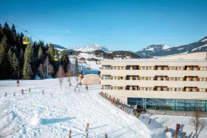 un bâtiment dans la neige avec une piste de ski dans l'établissement TUI BLUE Fieberbrunn, à Fieberbrunn