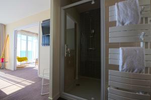 een badkamer met een douche en een glazen deur bij Les Flots - Hôtel et Restaurant face à l'océan - Châtelaillon-Plage in Châtelaillon-Plage