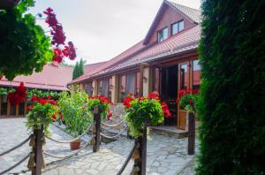 un bâtiment avec des géraniums rouges devant lui dans l'établissement Pensiunea Hubertus, à Bistriţa