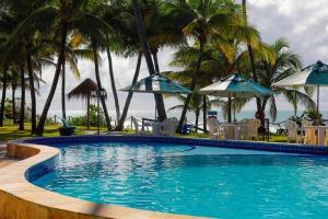 una piscina con sedie, ombrelloni e oceano di Pousada Ecoporto a Porto De Galinhas