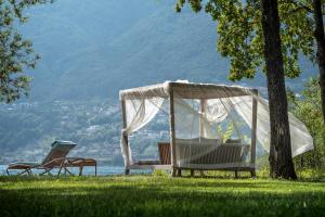 dos sillas y una hamaca en el césped cerca de un árbol en Castello del Sole Beach Resort&SPA, en Ascona