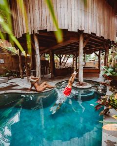 two people laying in a swimming pool at Gili Treehouse in Gili Trawangan