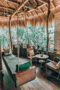 a room with a bed swing and a table at Gili Treehouse in Gili Trawangan