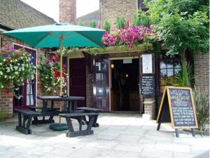 una mesa de picnic y una sombrilla frente a un edificio en The Wheatsheaf Inn, en Cuckfield